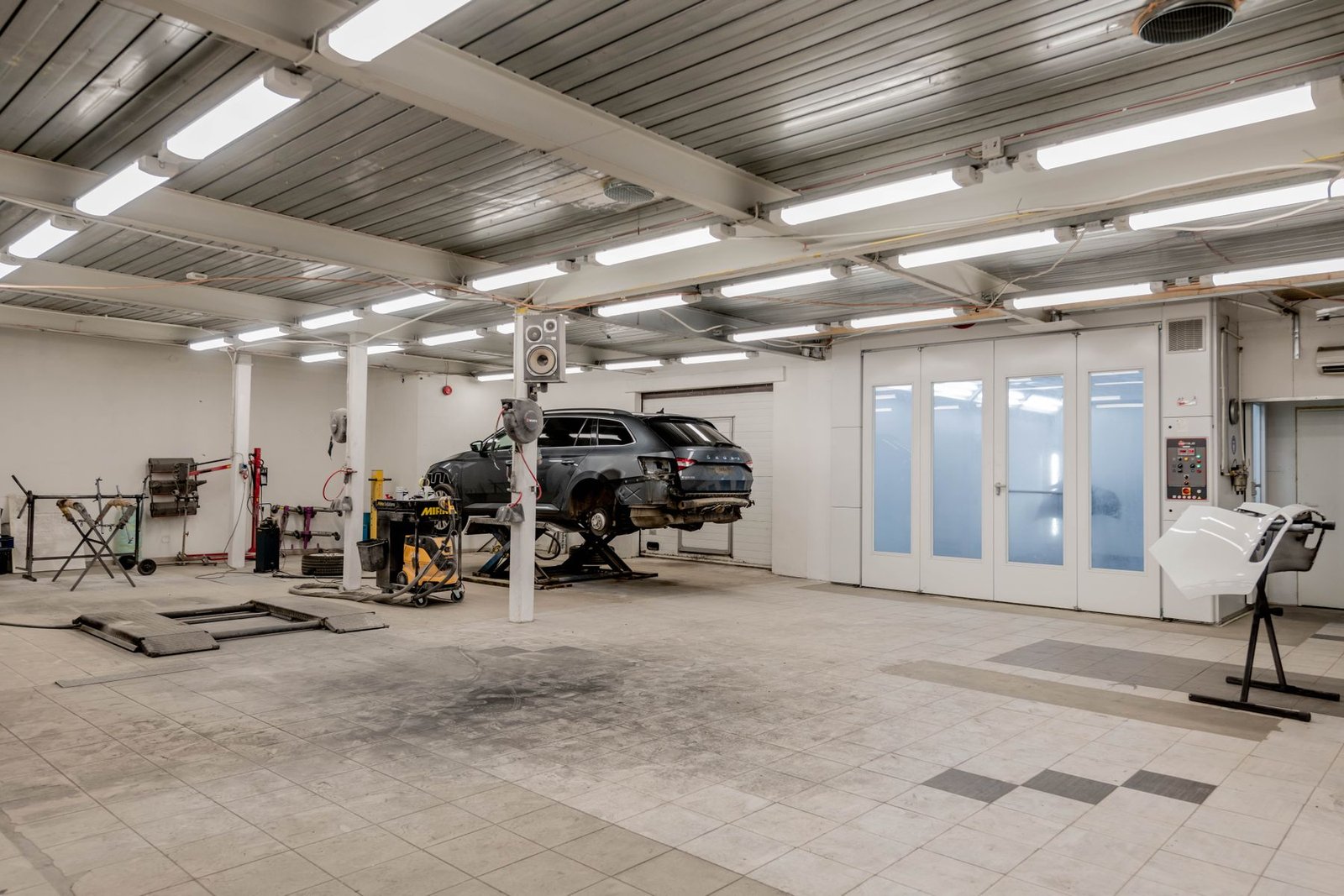 Interior of a modern auto repair garage with a vehicle raised on a lift